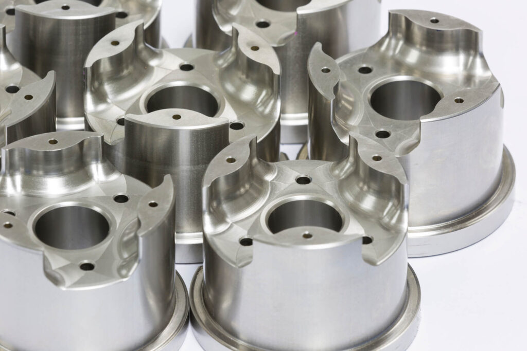 best metal casting, Close-up of several shiny metallic machine parts with cylindrical shapes and drilled holes, arranged closely together.