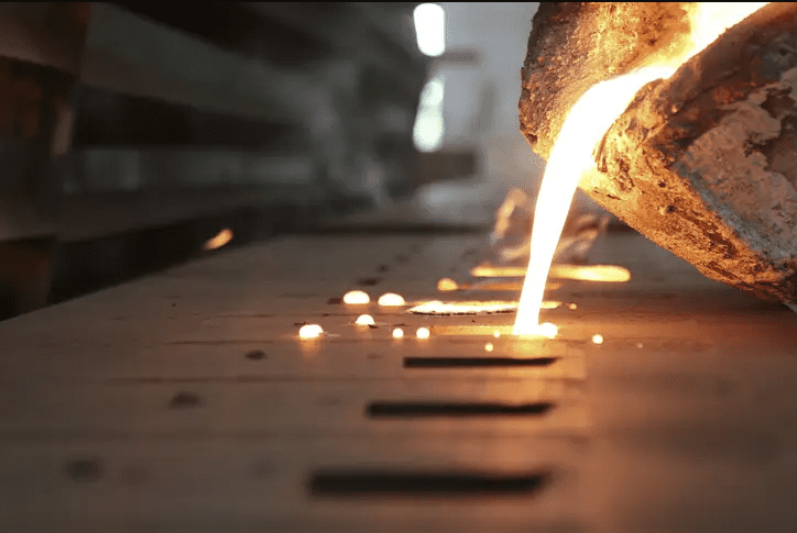 A metal casting company pours molten metal into a mold, demonstrating traditional metalworking and manufacturing techniques.