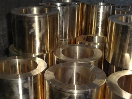 A close-up view of aluminum bronze casting components, featuring metallic cylindrical parts with shiny brass and silver surfaces stacked together.