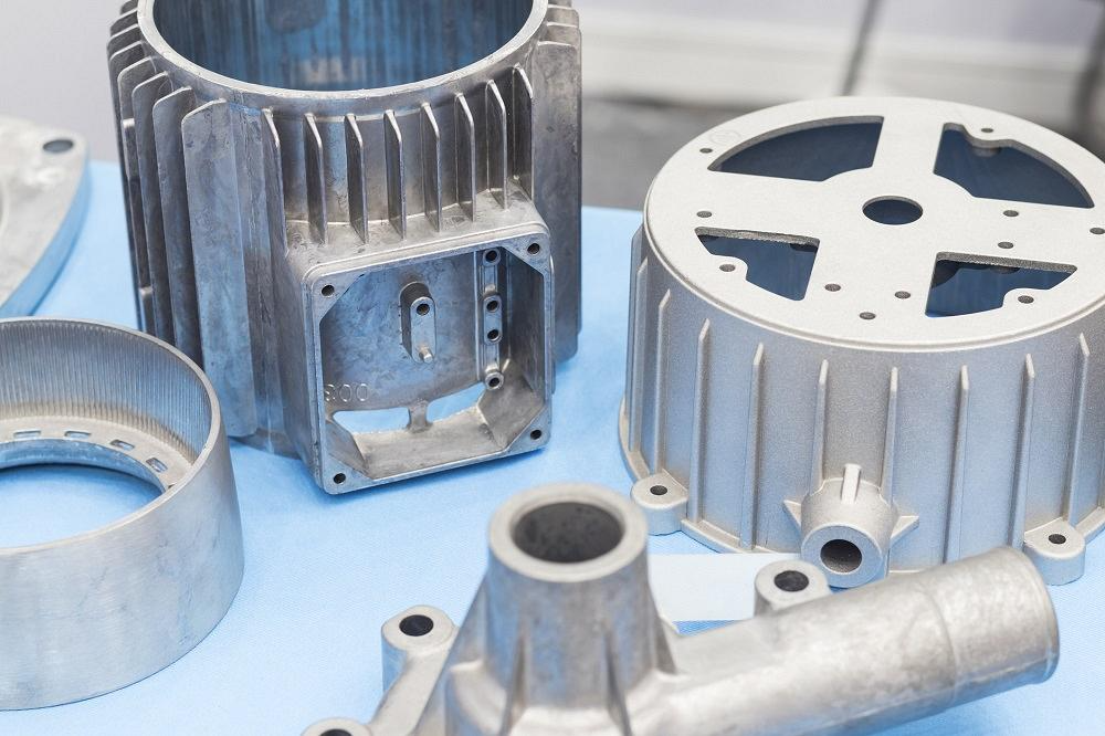Various aluminum mechanical parts arranged on a blue surface, showcasing a mix of intricate designs and textures.
