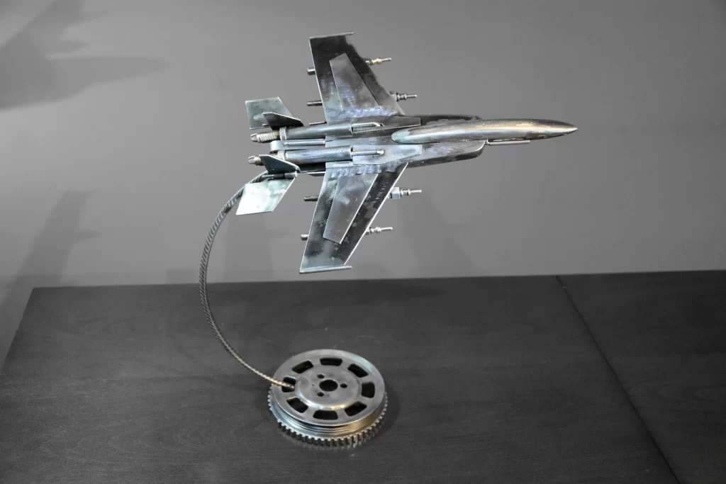 A detailed model of a fighter jet mounted on a circular base, showcasing a sleek metallic design and realistic features.