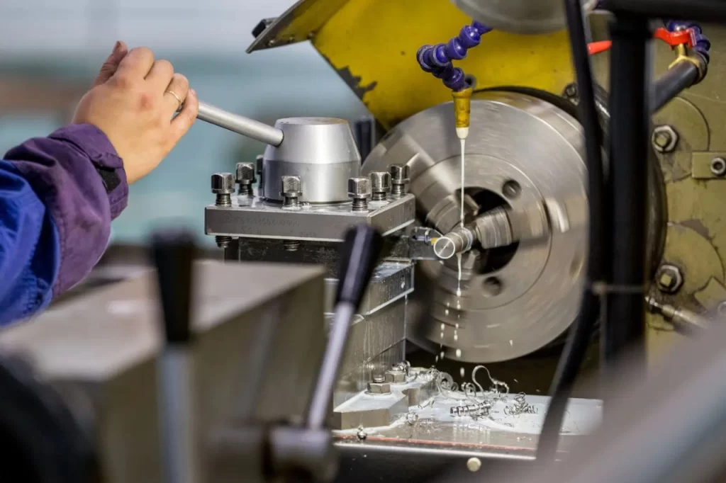 A technician adjusts machinery with a wrench in a workshop, focusing on lathe works, precision engineering, and manufacturing processes.