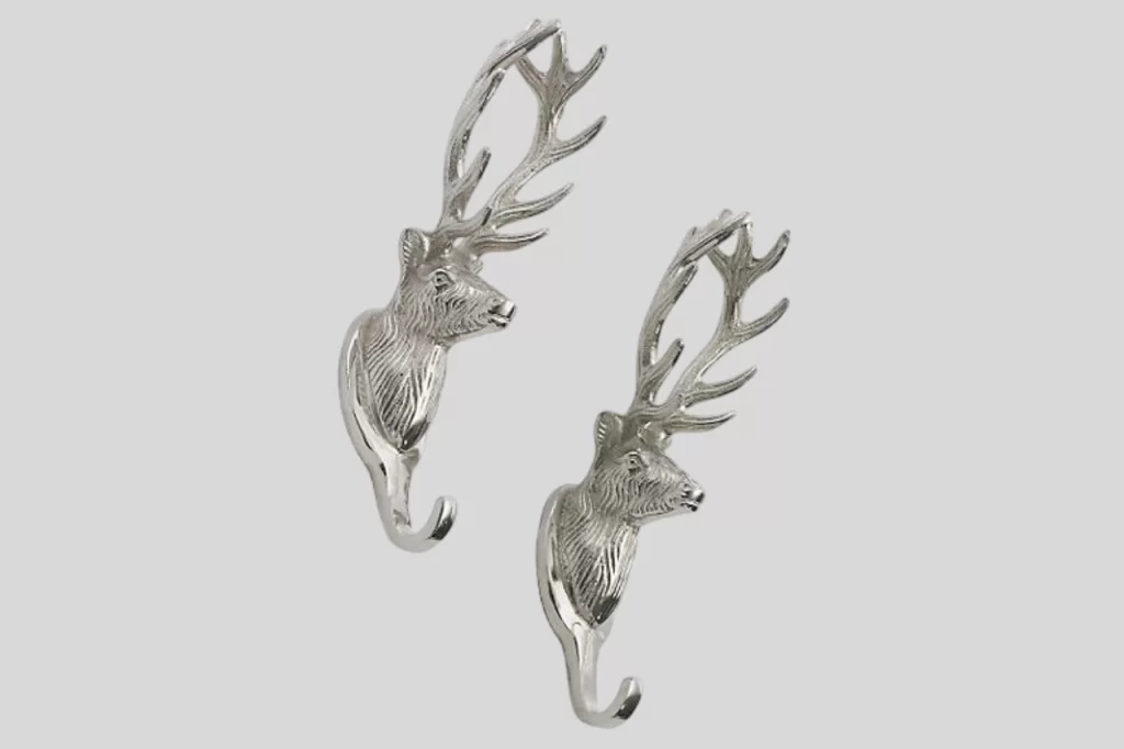Two ornate silver hooks shaped like deer heads with detailed antlers, ideal for home decor or coat hanging.