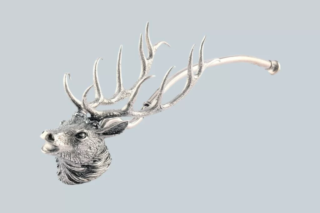 A decorative silver brooch shaped like a deer's head with intricate antlers, showcasing fine craftsmanship and detail.