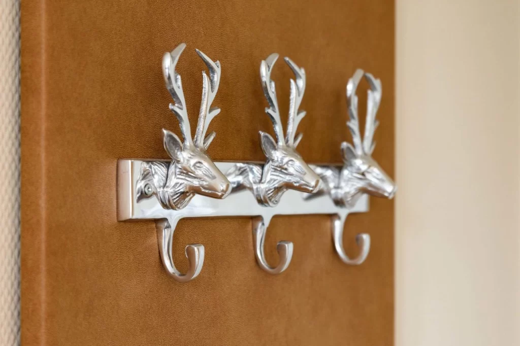 Silver antler coat hooks mounted on a textured brown background, adding a rustic touch to home decor.