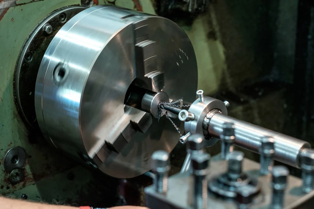 Close-up of a metal Lath Work UAE in action, shaping a cylindrical workpiece with metal shavings flying off.