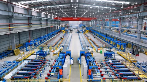 A spacious and well-lit factory interior with conveyor belts and industrial machinery lining parallel rows, conveying efficiency and precision. aluminum extrusion manufacturer